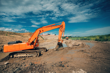 industrial excavator working on highway construction site. Details of excavator digging in water and dirt for viaduct construction