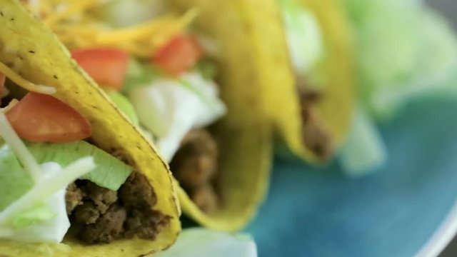 Close up of fresh beef tacos in hard yellow corn taco shell with sour cream and shredded cheese