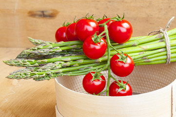 cherry tomatoes and a bunch of asparagus on the sieve