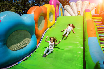 Gorgeous girls having fun on a slide on a sunny day.