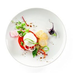 Delicious Italian caprese on a rustic wooden table. Healthy salad made of mozzarella cheese, tomatoes and herbs on a plate.