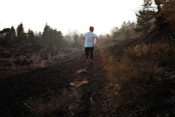 Homme qui court sur un volcan au coucher de soleil