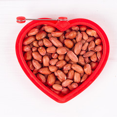 Raw peanuts in heart bowl.