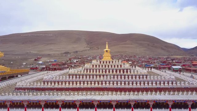 Aerial view of the pagodas with buddhist monks walking under at Yarchen Gar Monastery In Sichuan, China
