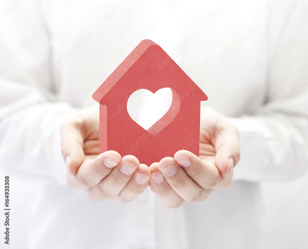 Wall mural Small red house with heart in hands 