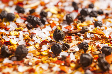 A very close view of coarsely ground red pepper, salt and whole black pepper seasoning.