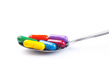 Spoon full of various pills on white background