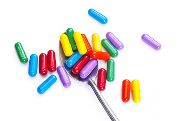 Spoon full of various pills on white background