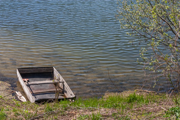 Naklejka premium Old wooden boat moored to the bank of the lake