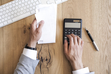 Hands holding bills and paying bills on table