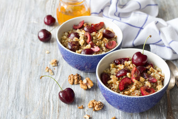 Healthy delicious vegan breakfast. Quinoa with fresh cherries, walnuts and honey on the blue background
