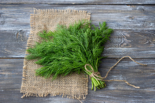 Bunch of fresh dill on a wooden surface with free space. Rustic style, selective focus