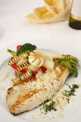 Hake fillet with grilled vegetables arranged on a plate, Traditional dish in elegant setting, Selective focus with soft light