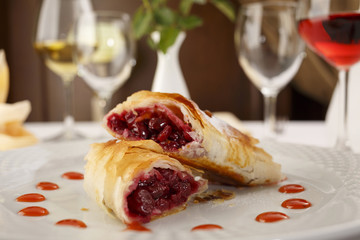 Cherry pie slice arranged on a plate, Wineglass in background, Traditional dessert in elegant setting, Selective focus with soft light