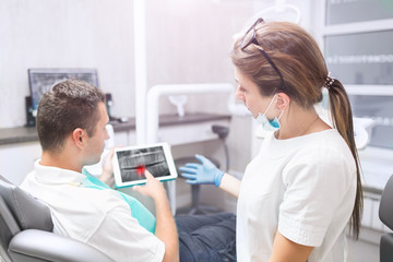 Obraz premium Portrait of a female dentist and young happy male patient in a dentist office. technology and health care concept - with tablet pc computer