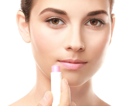 Closeup view of beautiful young woman applying lipstick, white background