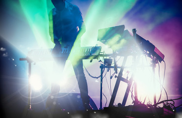 Fototapeta na wymiar disc jokey mixing on stage over illuminated smoke background - summer music festival