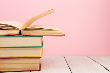 education and wisdom concept - open book on wooden table, color background