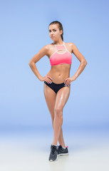 Muscular young woman athlete posing at studio