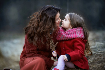 The girl and her mother sitting on the grass in the field in early spring