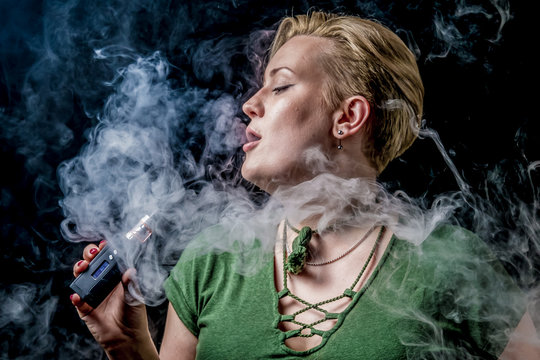 Female exhaling smoke and smoking electronic cigarette