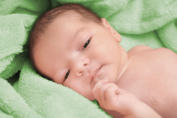 Cute newborn baby boy lying on soft plaid at home