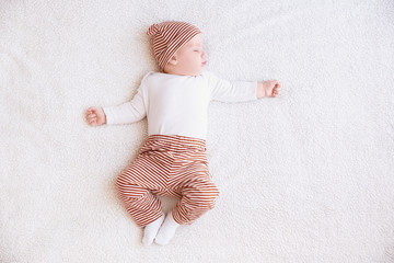 Cute little baby sleeping on plaid at home