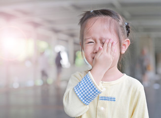 Asian little girl cover her eye with her hand.
