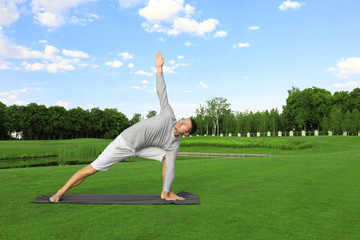 Fototapeta na wymiar Young man practicing yoga outdoors