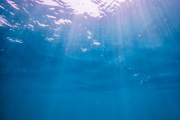Underwater turquoise texture in ocean. Sun rays in tropical sea.