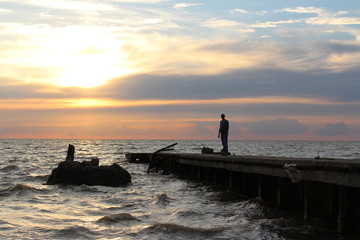 Naklejka na ściany i meble Man at the old marina at sunset
