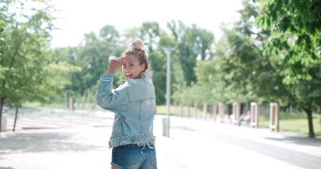 Happy stylish girl wearing denim jacket enjoying  time during sunny day in a park.