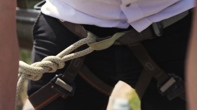Extreme professional climber who wears a suit prepares his safety ropes for a big climb