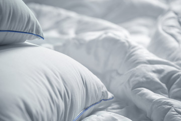 White pillows and blanket. Wrinkle messy blanket  in bedroom after waking up in the morning. Bed details. Duvet and blanket, an unmade bed in hotel bedroom with white blanket. Messy White Bed.
