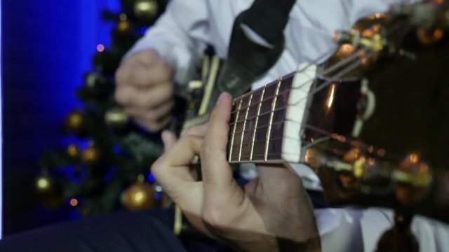 Guitarist Playing Electro Guitar on the background of Christmas tree Slow Motion Effect . Close-up