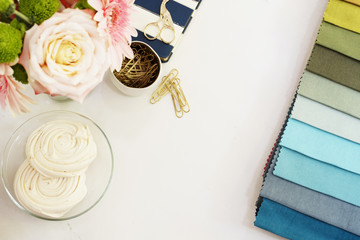 Fabric samples on the table. Freelance fashion comfortable femininity workspace in flat lay style with flowers on white marble background. Top view, bright, pink and gold