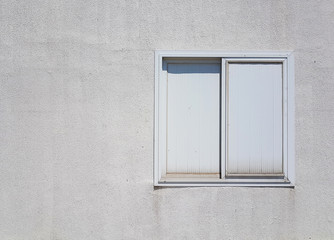 white plastic window on rough white concrete wall