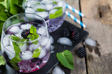 Blackberry mojito and ingredients on rustic background