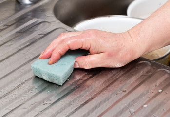 The cook wipes the sink with a rag
