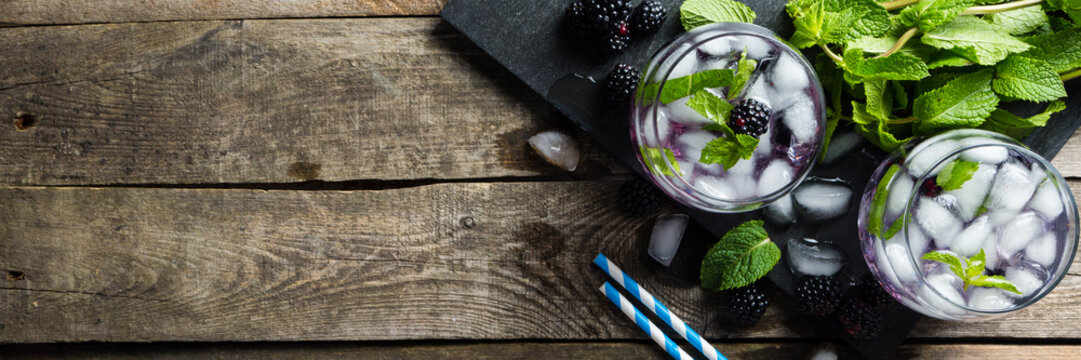 Blackberry mojito and ingredients on rustic background