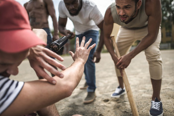 group of multiethnic men attacking other one with baseball bats