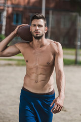 young handsome male football player with ball on court