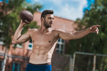 young handsome male football player with ball on court