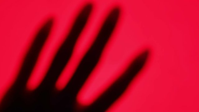 Abstraction. Beautiful female hand silhouette on abstract red background. Sensual red light