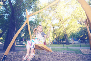 Happy little girl with enjoy riding on a swing