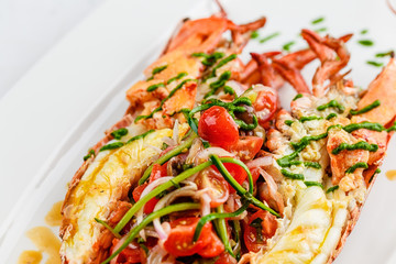 Italian cuisine. Whole lobster baked and sliced in half Served with tomato salad and sauce on white plate