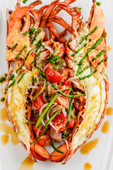Italian cuisine. Whole lobster baked and sliced in half Served with tomato salad and sauce on white plate
