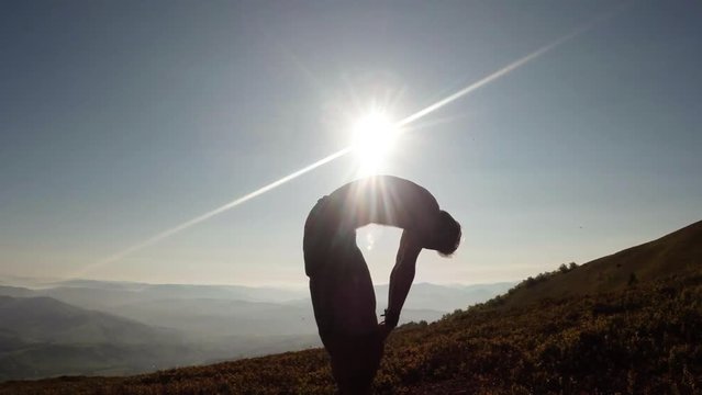 Silhouette of a Man Doing Yoga Exercises Under the Morning Sun on Mountain Tops Standing Forward Bend Uttanasana, Crescent Moon Ashta Chandrasana