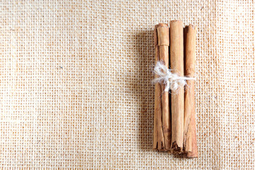 Some tied cinnamon sticks on a burlap fabric. Empty copy space for Editor's text.
