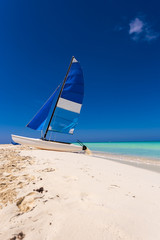 Fototapeta premium Sailboat on the sandy beach of the Playa Paradise of the island of Cayo Largo, Cuba. Copy space for text. Vertical.